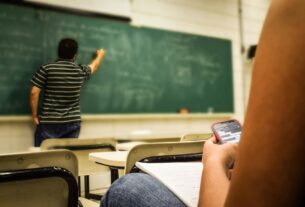 man in black and white polo shirt beside writing board